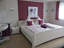 Bild vom Doppelbett vor violetter Wand